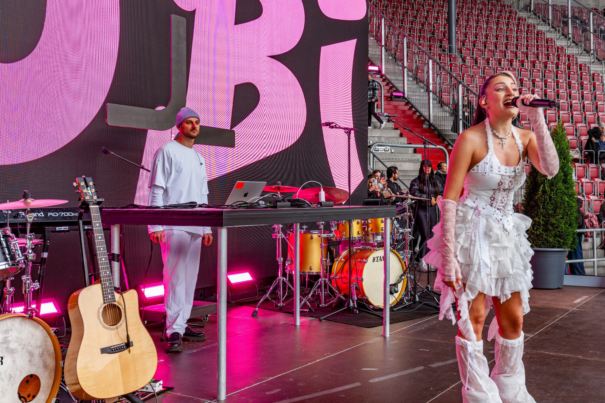 Rapperin Rubi in Weiß vor dem Namensschriftzug, WWK Arena Augsburg / Schulwerk